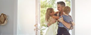 A dad hugging his children at the front door, call a top rated Hinsdale family law attorney for help with your child support case.