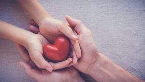 An adult and child hands holding a red heart stone, contact the Lombard child custody lawyers for help with your parenting time case.