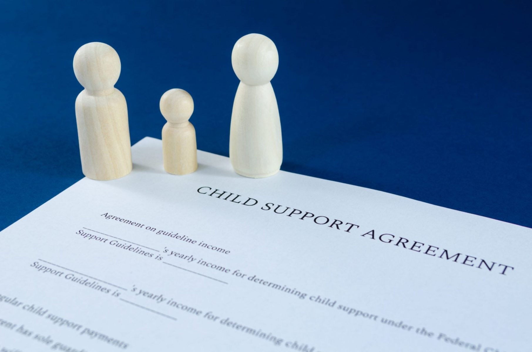 A wooden figurine family stands on a child support agreement document on the desk of an Oak Brook divorce attorney.