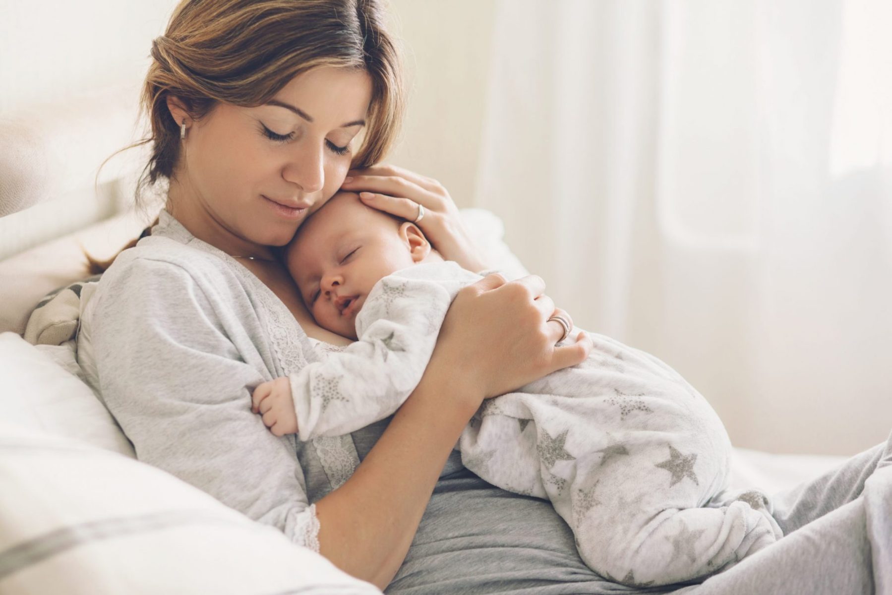 Woman holding a small sleeping baby, if deciding to end marriage, meet with a good Oak Brook divorce lawyer.