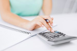 Woman typing on calculator, if you starting the divorce process meet with the best Naperville divorce attorney.