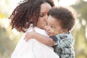 A mom holding and kissing her small son, if deciding to end marriage, meet with a top rated Naperville divorce attorney.
