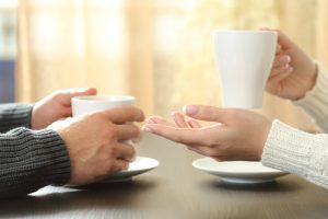 A couple holding coffee cups at table, if deciding to end marriage, meet with a top rated Elmhurst divorce attorney.