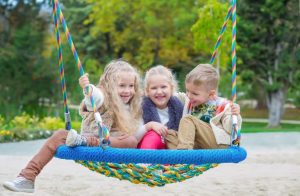 Three children on a swing together laughing representing the need for a Hinsdale child support lawyer.