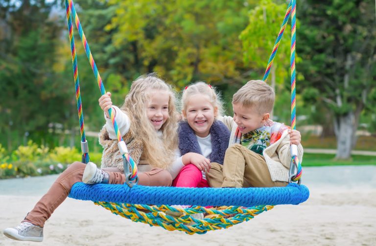 Three children on a swing together laughing representing the need for a Hinsdale child support lawyer.