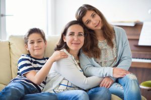A mom sitting on a couch close to her two children representing how you should call a Mt. Prospect divorce lawyer.