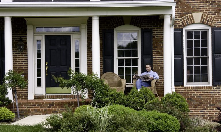 Man sitting on the porch of a brick house representing how you should call an Oak Brook divorce lawyer.