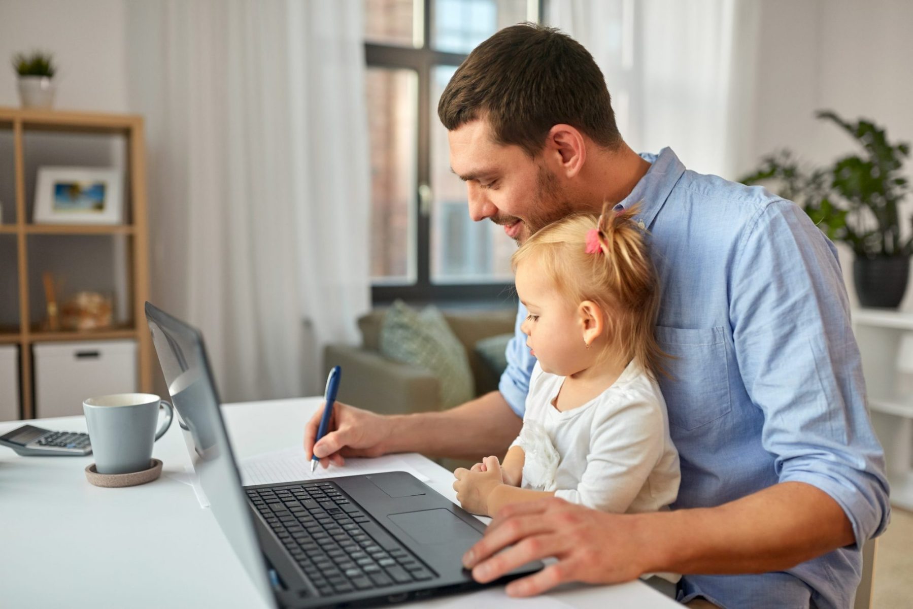 A dad working at his computer with a little girl on his lap representing the need for a Naperville family law attorney.