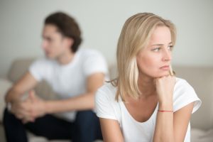 An unhappy man and woman sit in a room looking away from each other before contacting a Naperville divorce attorney.