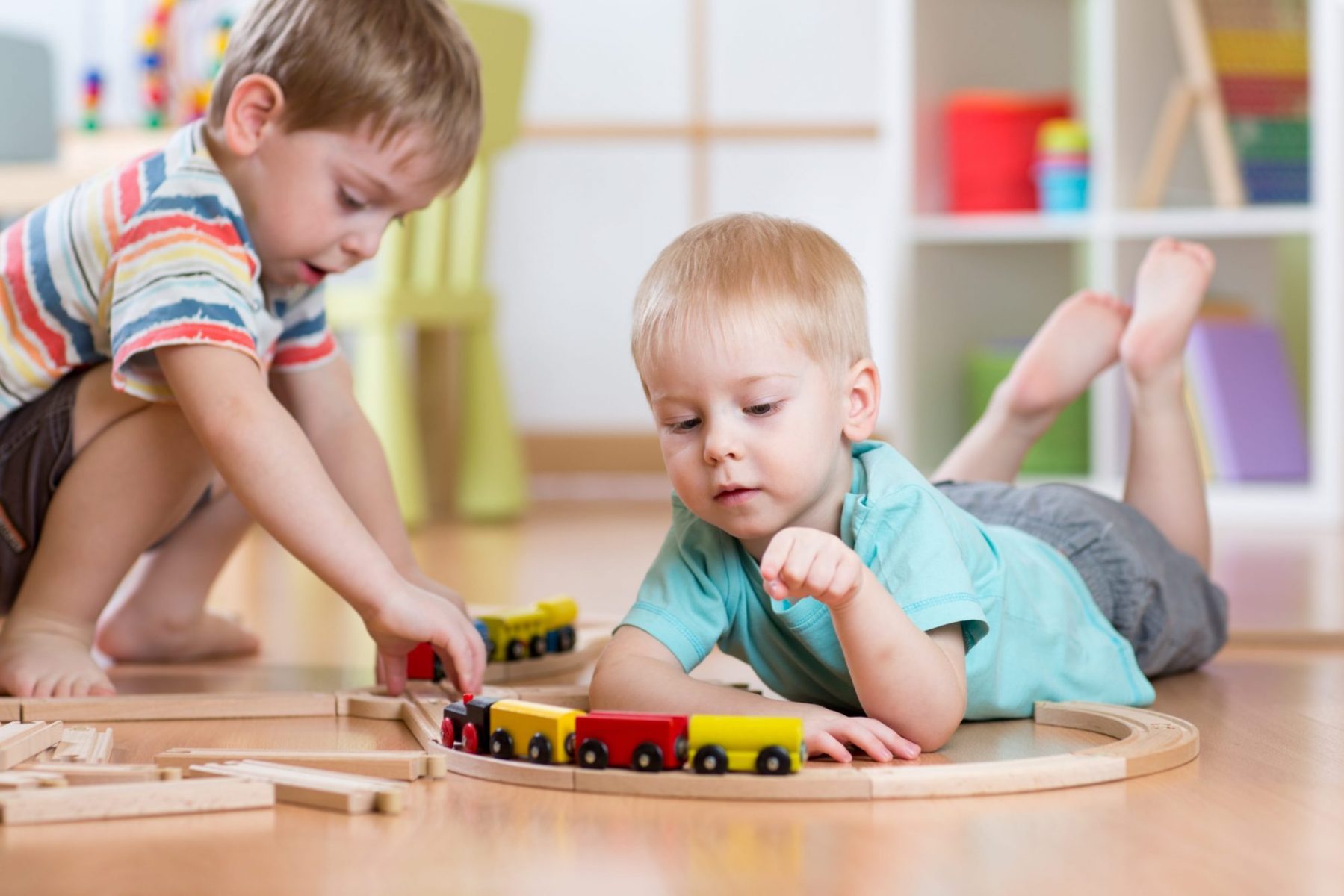 Two small boys playing on floor with toy train, when needing to develop a fair parenting plan meet with Lombard child custody attorney before meeting with a judge.