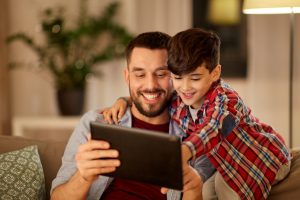 A man and little boy looking at a tablet, for help with parenting plan consult with Oak Brook Custody Lawyer.