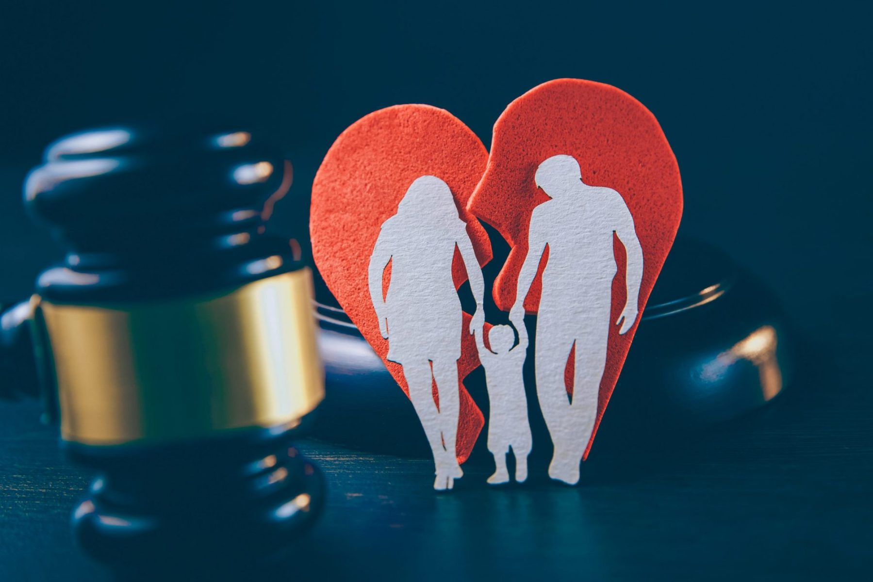 A gavel with broken heart and cutout of parents with child, consult with Wheaton child custody lawyer for help figuring out your parenting plan.