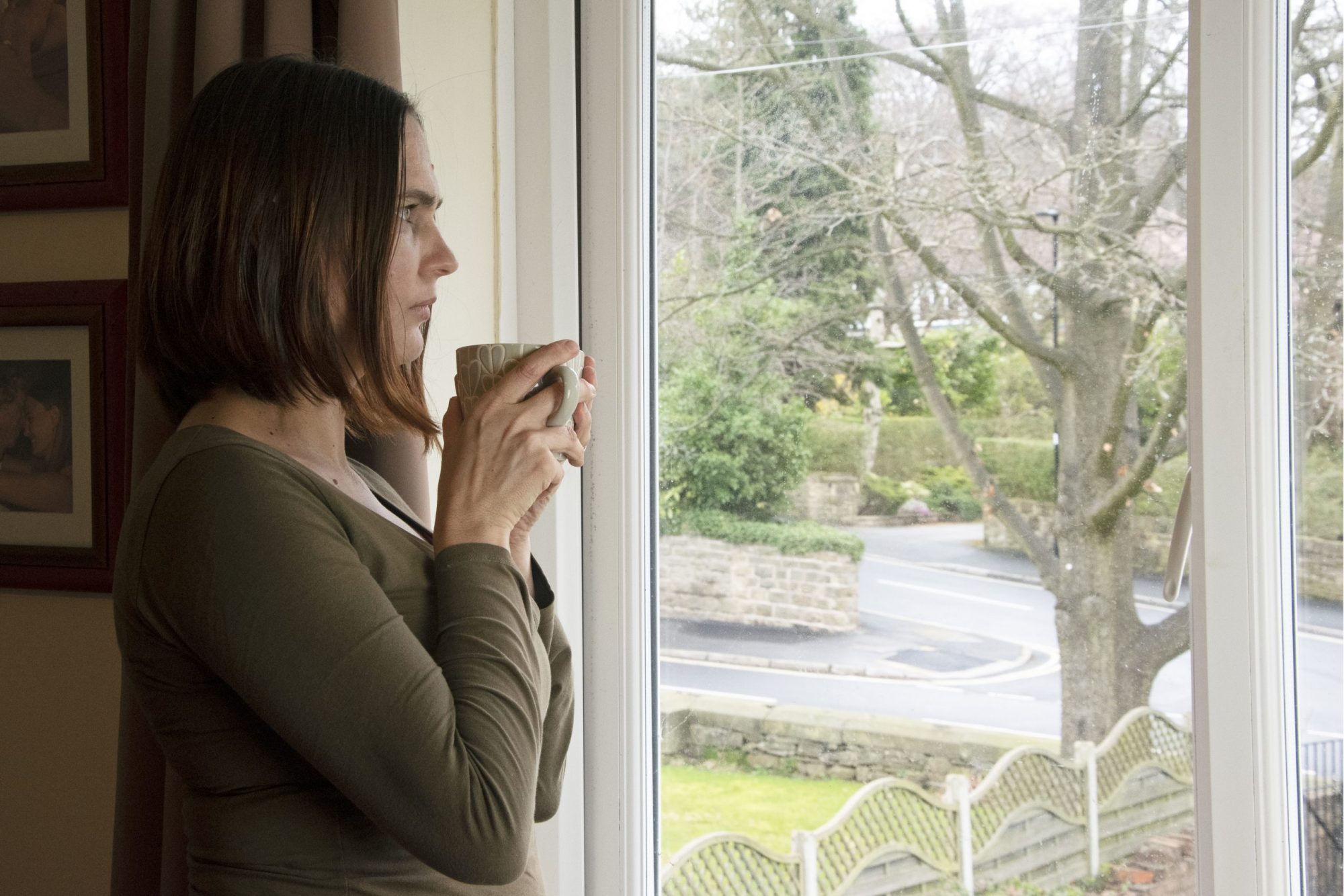 Woman looking out window holding mug, when deciding to end marriage call Chicago divorce lawyers for help with divorce process.