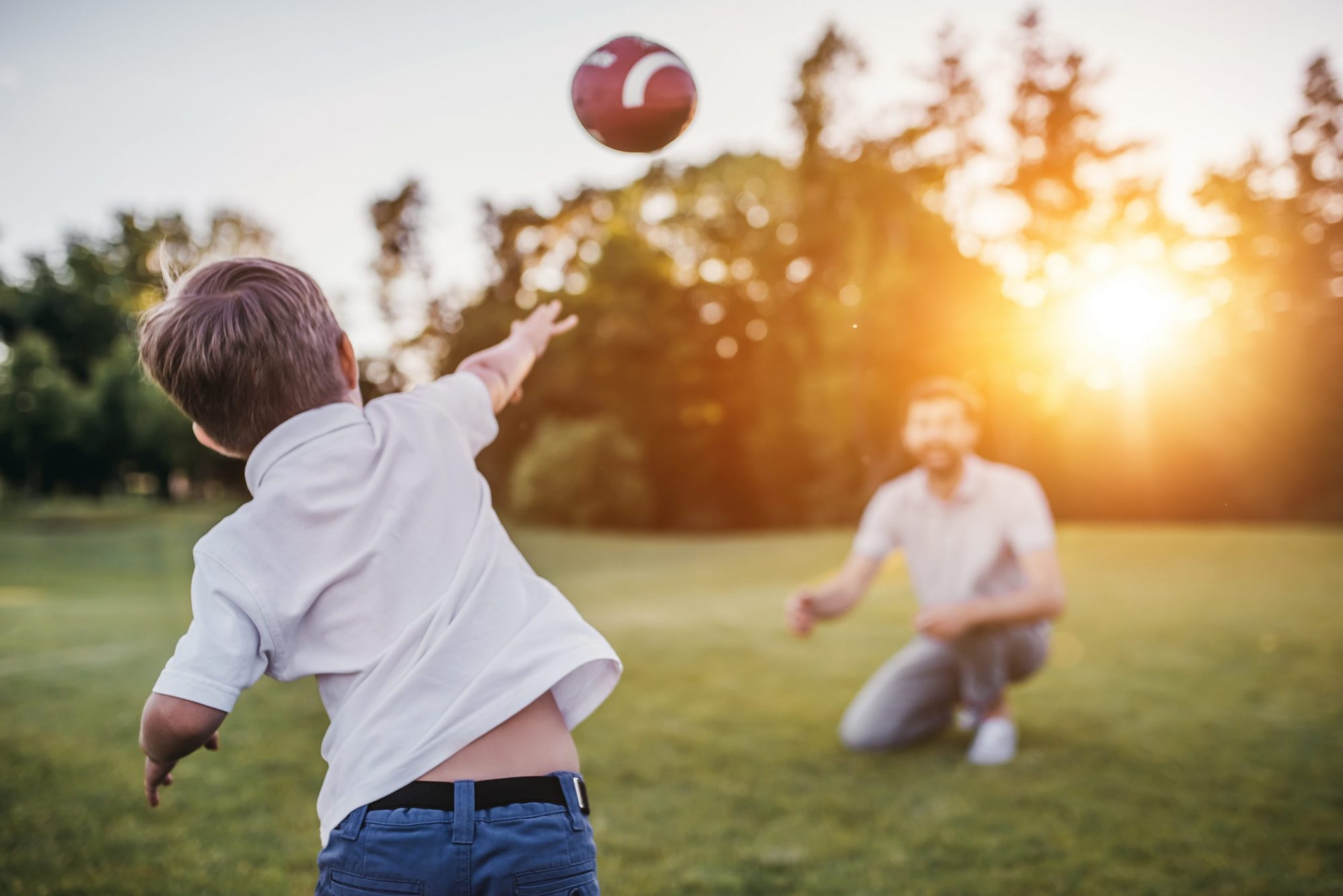 A boy playing catch with football with dad, a Chicago parenting plan attorney can assist with any custody issues.