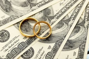 Two gold wedding rings on hundred dollar bills when needing advice on financial issues with Divorce Lawyers in Glenview.